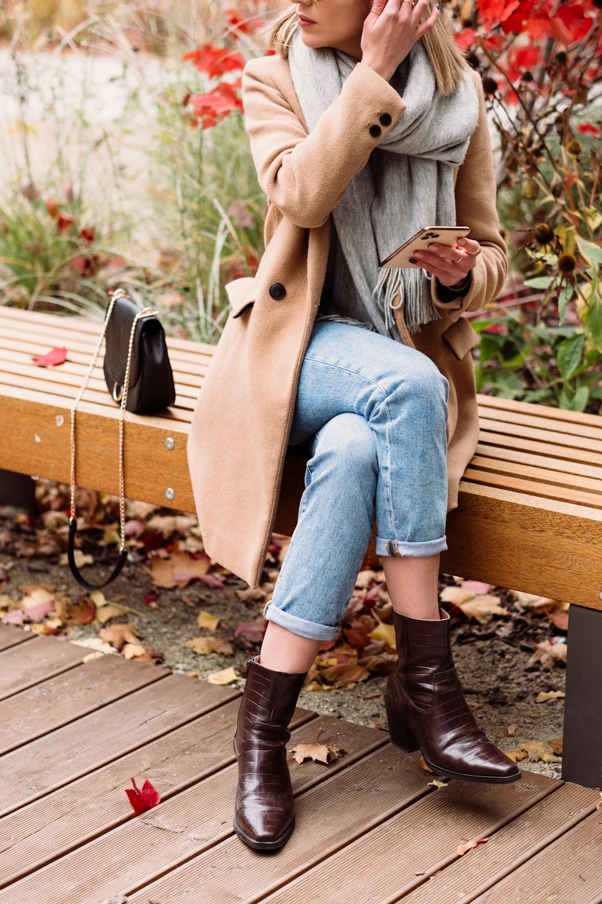 Woman in a deep burgundy coat crossing a leafy autumn street
