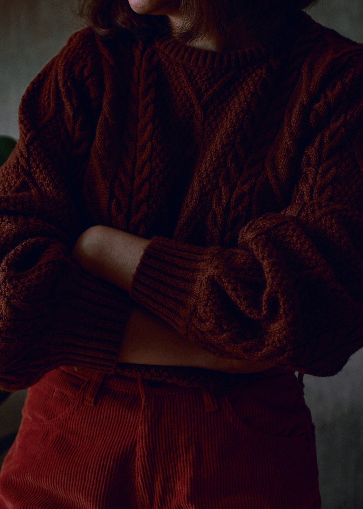 Softly lit portrait of a woman in a cream ribbed knit among autumn leaves