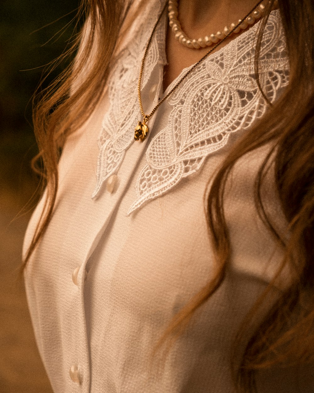 Close up of layered gold necklaces over a cream lace collar