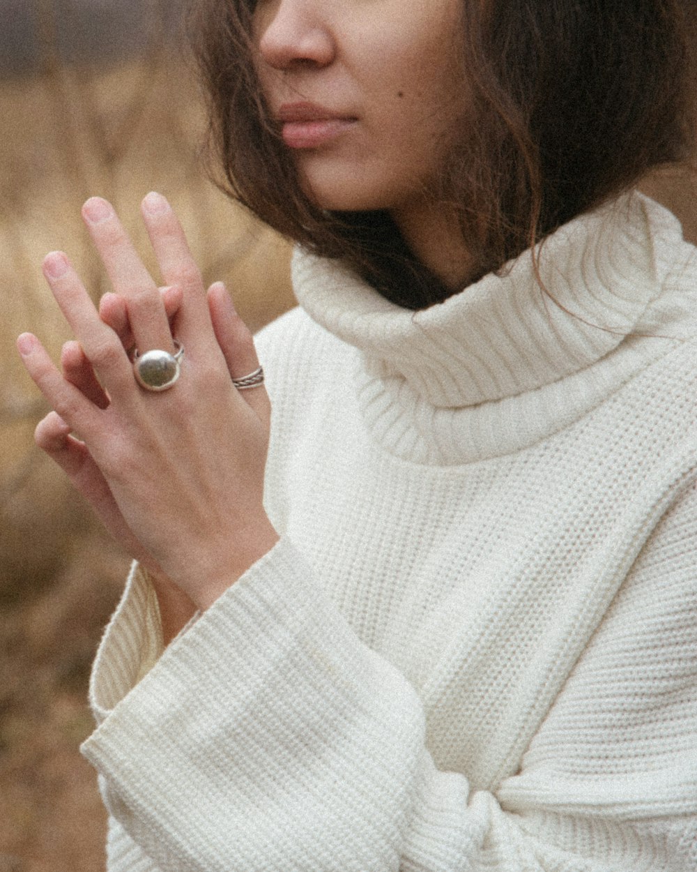 Woman in a cream chunky knit roll neck in a warm autumn field